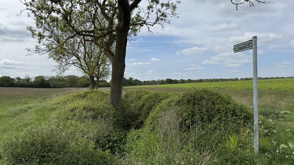 View of the young River Beane in open countryside with a public footpath sign alongside